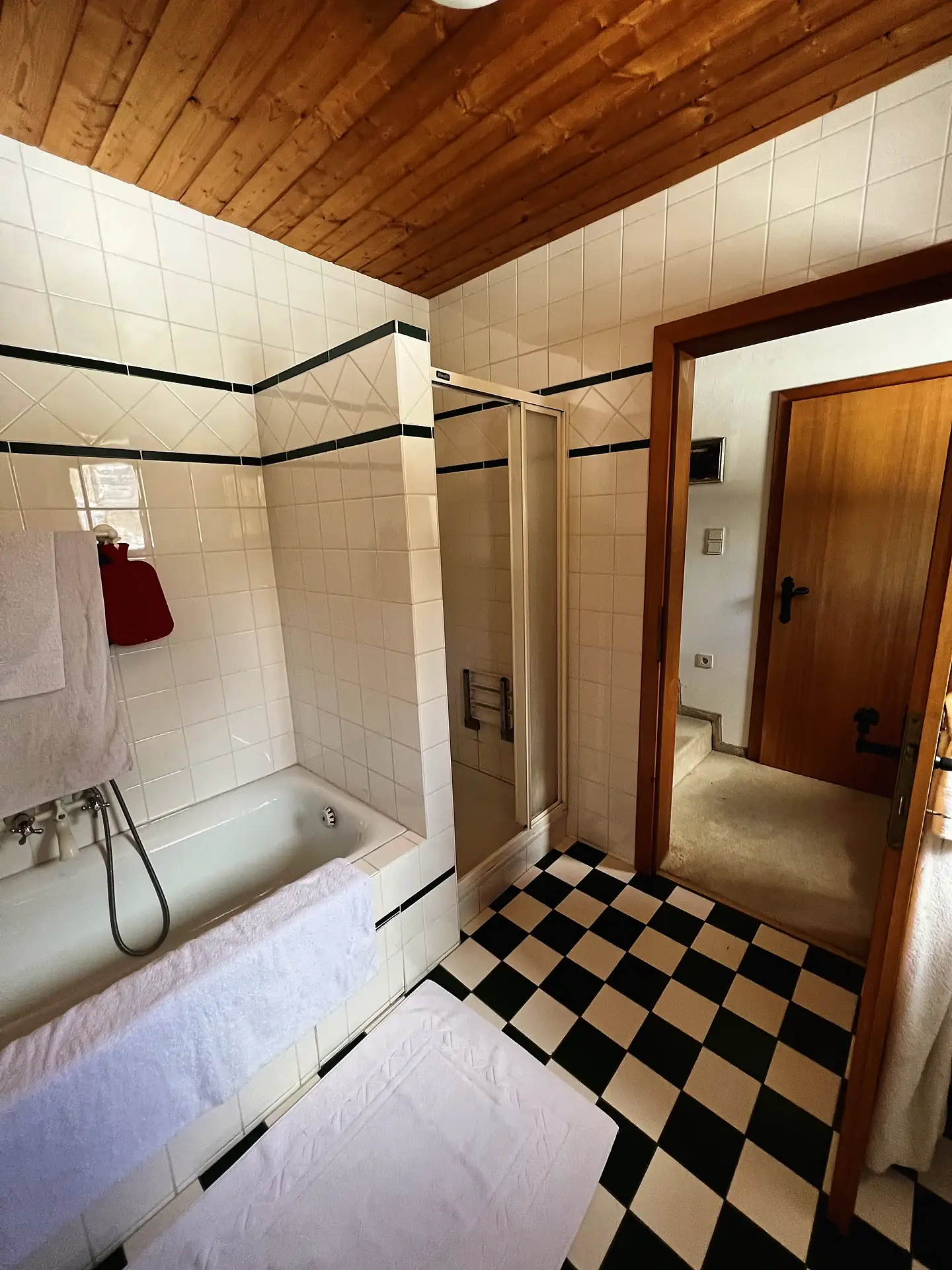Badezimmer mit Badewanne, separater Duschkabine und Holzdecke.