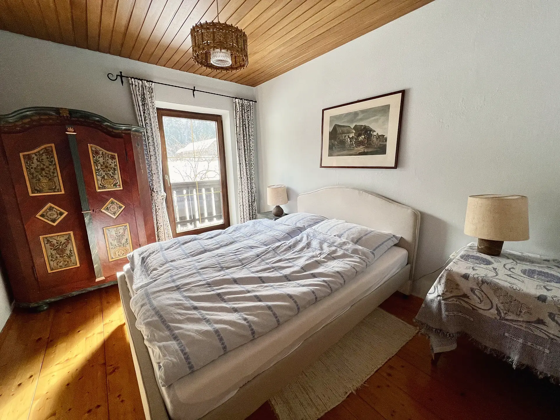 Gleiches Schlafzimmer, Blick auf Doppelbett, Nachttisch und Holzdecke.